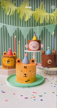 there are three cakes decorated with animals on top of each other and candles in the shape of monkeys