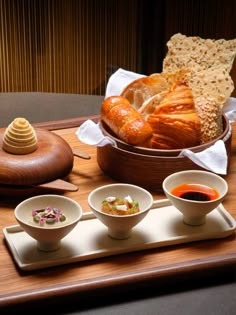 there are three bowls with food in them on the table next to some breads