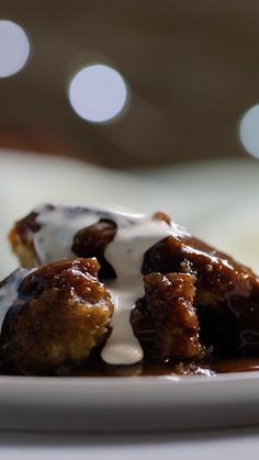 a white plate topped with dessert covered in icing and sauce on top of a table