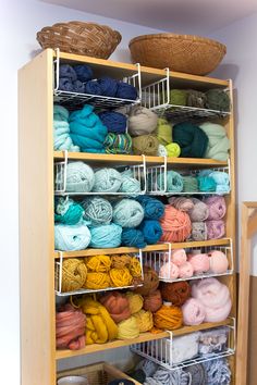 a shelf filled with lots of yarn next to a basket full of balls of yarn