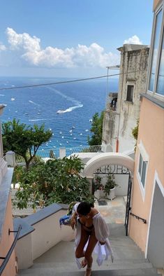 a woman is walking down some stairs near the ocean