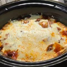 a black crock pot filled with cheese and meat