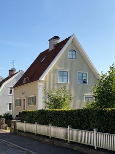 a white house with a red roof next to a fence