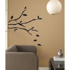 a living room with a couch, chair and tree branch wall decal