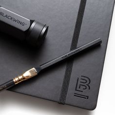 the blackwing brush is laying on top of a notebook with its pen resting on it