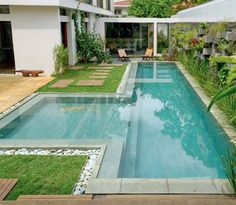 an empty swimming pool in the middle of a yard with grass and plants around it