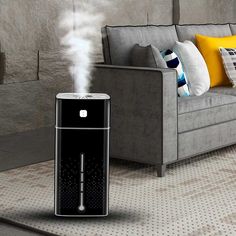 an air purifier sitting on the floor next to a couch with pillows