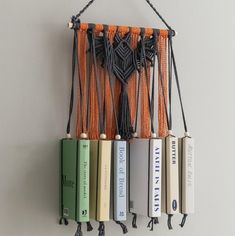 an assortment of books hanging on a wall with tassels attached to the book ends