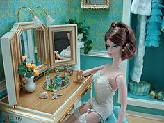 a doll sitting at a dressing table in front of a mirror