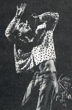 a black and white photo of a man with his arms in the air while performing on stage