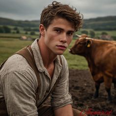 a young man sitting in front of a brown cow