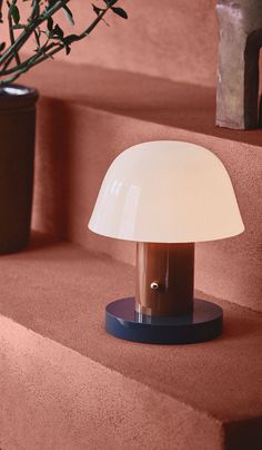 a lamp sitting on top of a table next to a potted plant