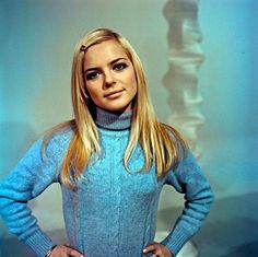 a woman standing in front of a wall with her hands on her hips and looking at the camera