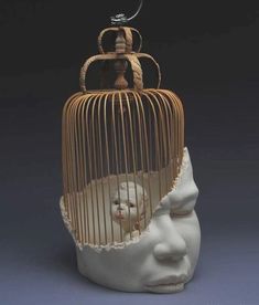 a sculpture of a human head with a bird in a cage