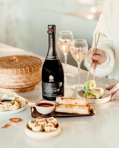 a woman sitting at a table with food and wine