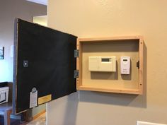 an electrical device mounted to the wall in a wooden box with a blackboard behind it