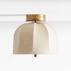 a light fixture with a beige shade on it's side and a gold ring around the neck