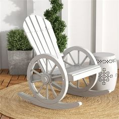 a white rocking chair sitting on top of a rug next to a potted plant