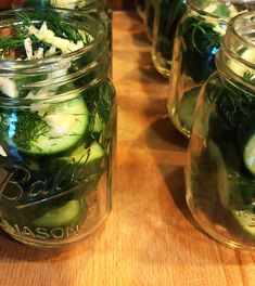 several jars filled with cucumbers sitting on top of a wooden table