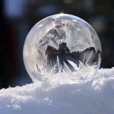 a snow globe sitting on top of a pile of snow covered in ice and snow flakes