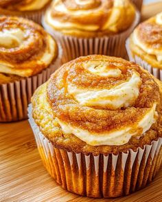 cinnamon roll cupcakes with cream cheese frosting on top sitting on a wooden table