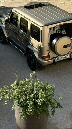 a silver car parked next to a tree in a parking lot with its door open