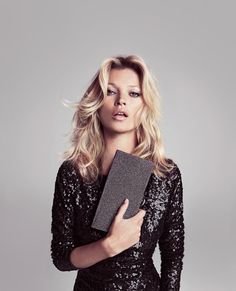 a beautiful blond woman holding a book in her hands and looking at the camera while wearing a black sequined dress