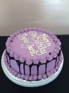 a birthday cake with purple frosting on a table