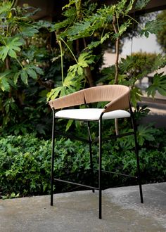 a wooden chair sitting on top of a cement floor next to green bushes and trees