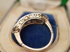 an ornate gold ring sitting on top of a blue velvet case in a jewelry box