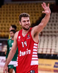 a male basketball player in a red uniform is holding his hand up to the sky