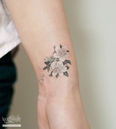 a woman's hand with a flower tattoo on the left side of her wrist