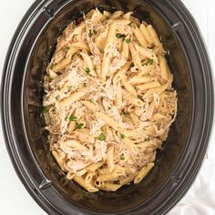 a crock pot filled with pasta and chicken in it on top of a white table