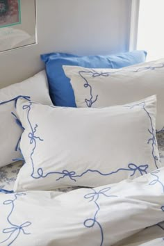 a bed with blue and white pillows on top of it next to a framed picture