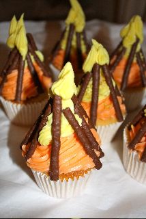 several cupcakes with yellow frosting and chocolate decorations on top are sitting on a white tablecloth