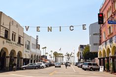 cars are parked on the street in front of buildings and an overhead sign that reads venice