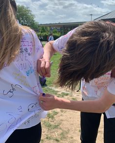 two girls with writing on their t - shirts are holding hands over each other's shoulders