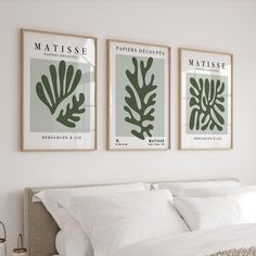 three framed prints on the wall above a bed in a room with white sheets and pillows