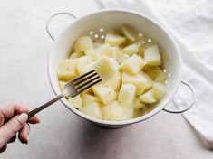 a person holding a fork in a bowl of potatoes