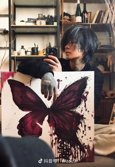 a person holding up a painting with a butterfly on it