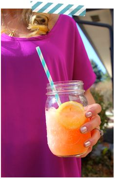 a woman holding a mason jar filled with orange juice