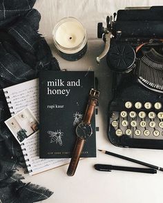 an old fashioned typewriter sitting on top of a table next to a book and pen