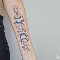 a woman with a tattoo on her arm that is decorated with flowers and crescents