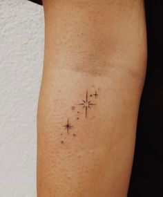 a small cross tattoo on the right arm and leg, with stars in it's center