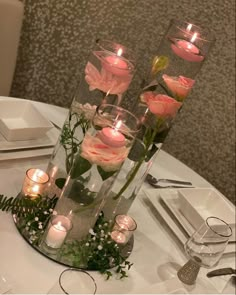 flowers and candles are arranged in glass vases on a table