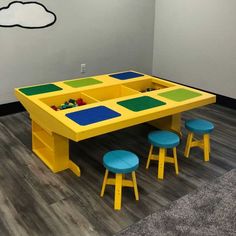 a yellow table with legos on it and blue stools