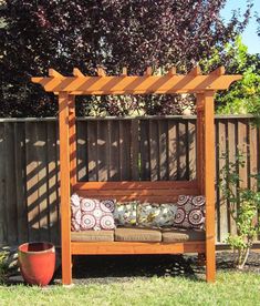 a wooden bench sitting in the middle of a yard next to a fence and potted plant