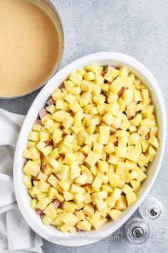 a white bowl filled with chopped pineapple next to a cup of coffee