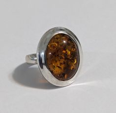 Magnificent vintage Sterling Silver And Amber Ring Size 7.25.  Good vintage condition. This cognac amber ring is absolutely beautiful and accented with embossed leaves on the side.  Amber cabochon measures 3/4" in length by 1/2" in width. or 18 x 14 mm The face of the ring is 1 by 3/4 inches or 24 x19 mm It weighs 10.1 grams; is marked 925 (sterling silver), and has been acid-tested.  It will come in a gift box Vintage Baltic Amber Jewelry For Formal Occasions, Vintage Brown Ring With Polished Finish, Vintage Amber Hallmarked Rings, Brown Hallmarked Vintage Ring, Vintage Brown Hallmarked Ring, Vintage Oval Cabochon Amber Ring, Classic Amber Oval Cabochon Ring, Vintage Amber Oval Cabochon Ring, Antique Oval Amber Ring