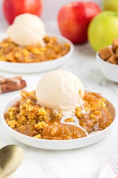 two white bowls filled with apple crisp and ice cream on top of a marble table